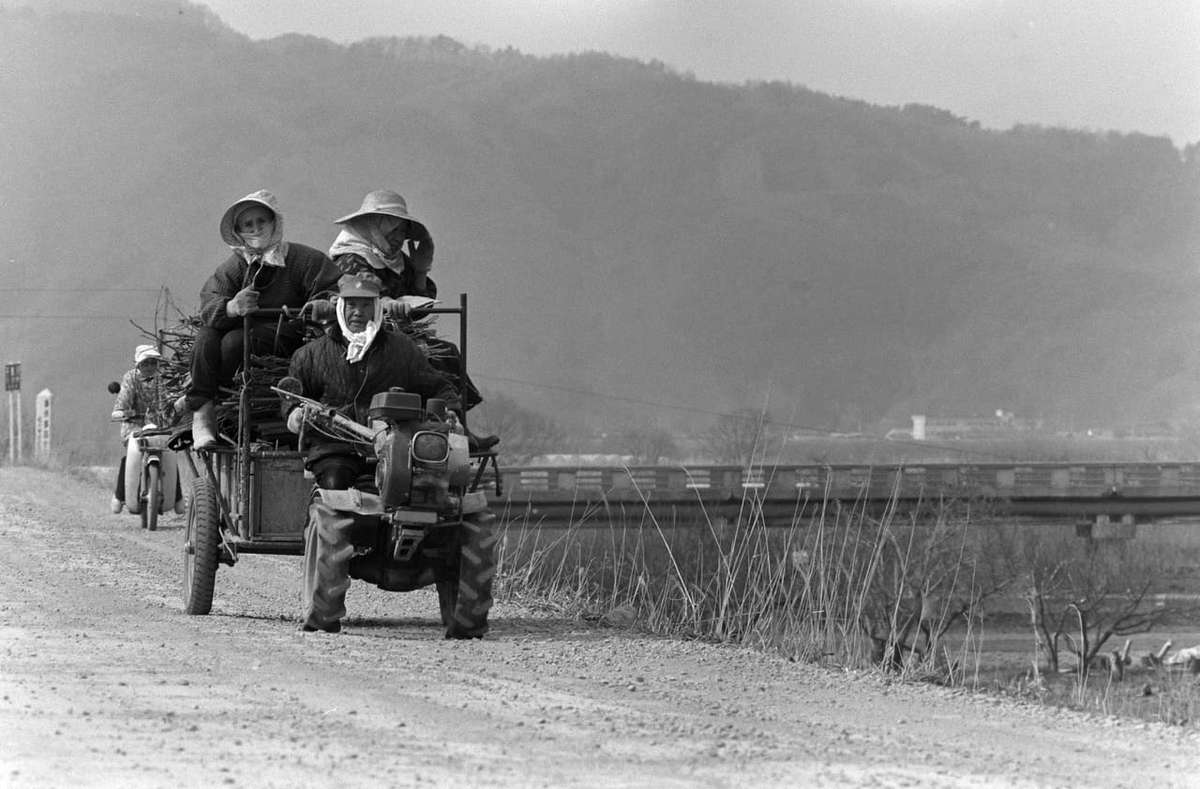 耕運機で畑へ向かう人々